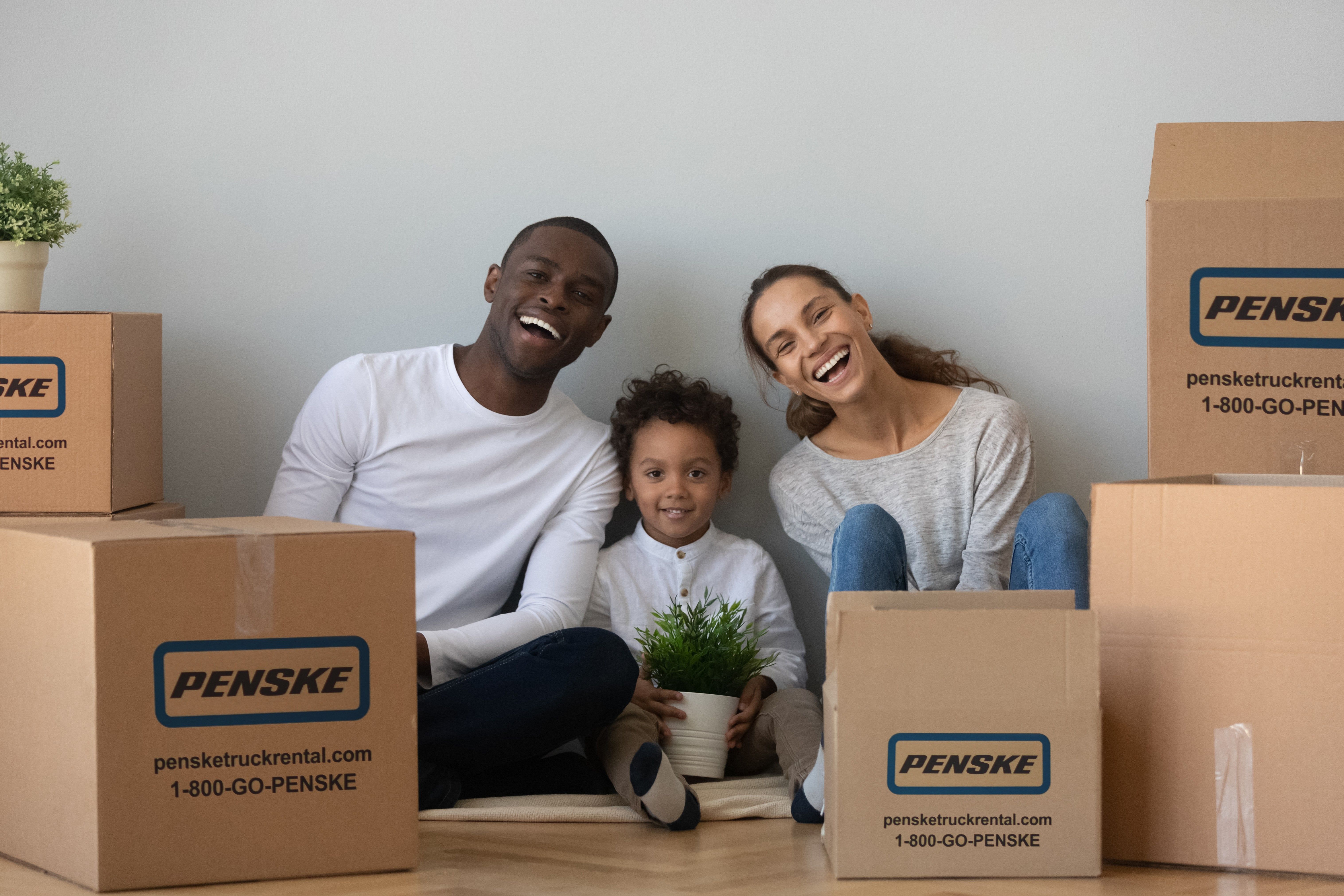 A woman, man and child sit among boxes ready to move.