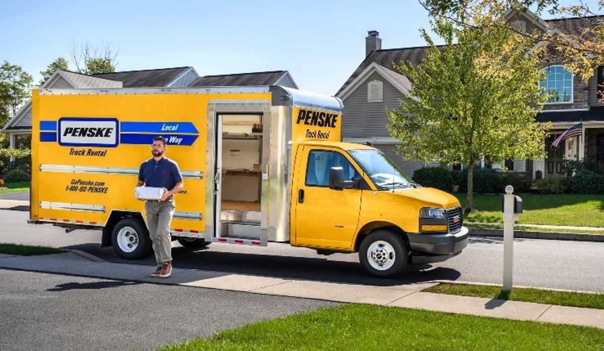 A yellow Penske box truck with shelves and curbside door.