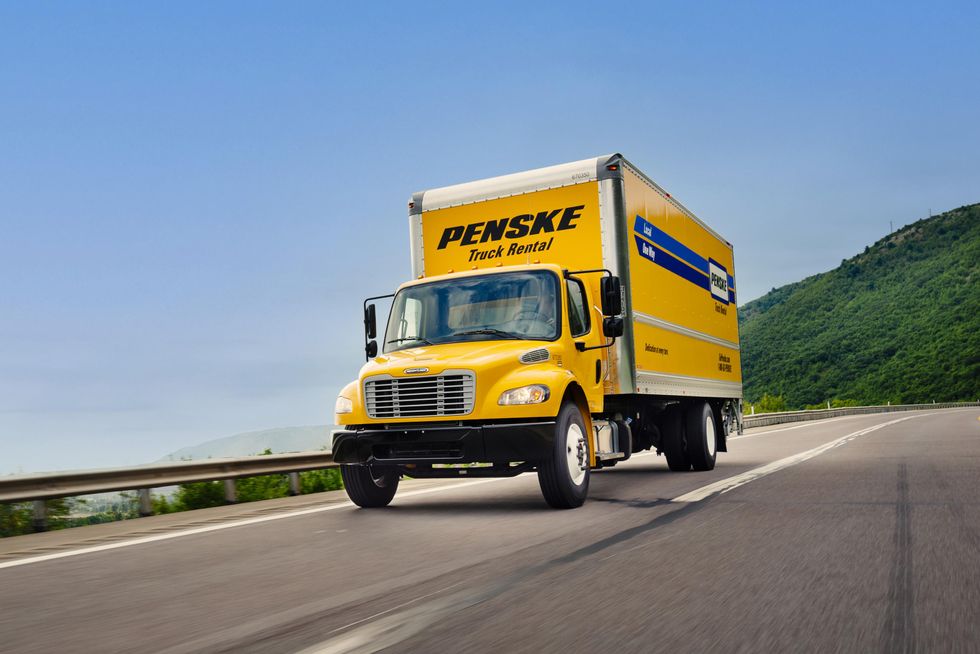 A yellow Penske truck drives on the highway.