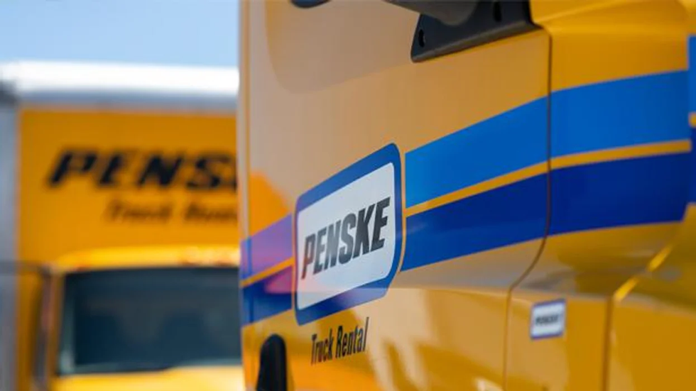 Close-up of a Penske logo on a yellow truck.