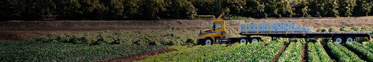 Flatbed trailer hauling items through a farm field.