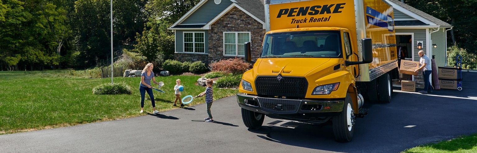 Little girl in front of moving Penske moving truck