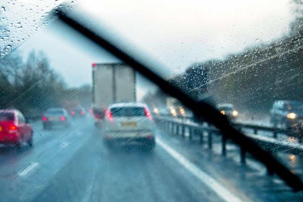 View through the inside of a car through a wet windshield at traffic on a rainy highway. 